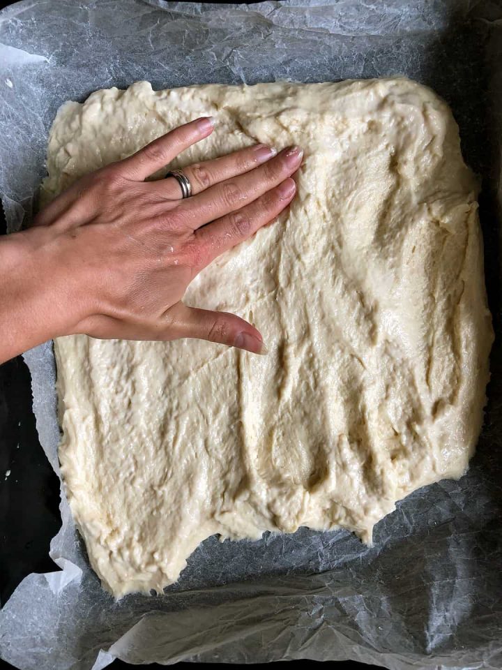 Stretching a yeast cake dough with wet hands.