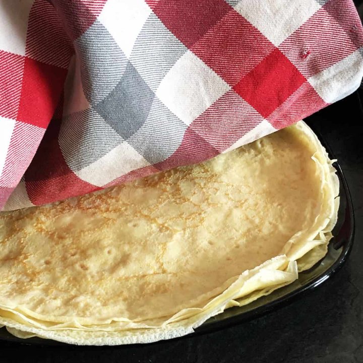 Pilled pancakes on the plate covered with a cloth