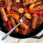 Sausages and bell peppers in a cast iron pan.