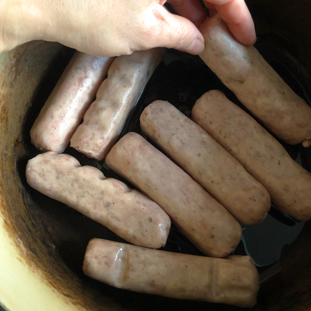 Raw pork sausages in a pot.